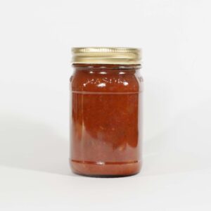 A glass jar filled with reddish-brown sauce and a gold lid.