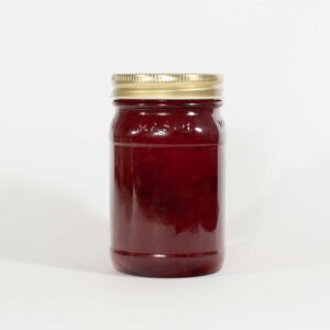 A jar filled with dark red jam or jelly with a gold lid.