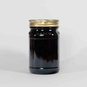 A glass jar filled with dark liquid and sealed with a gold lid.