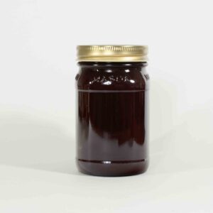 A glass jar filled with dark liquid, sealed with a gold lid.